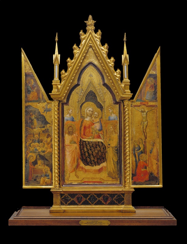 Small Gothic tabernacle by Allegretto Nuzi in an elaborate gilded frame with pinnacles and twisted columns: in the centre the Virgin enthroned under a canopy with a starry vault, holding the Christ Child, flanked by two angels, Saint John the Baptist and a female saint; on the left wing the Nativity with the ox and ass, Joseph and a choir of angels, and above an angel announcing to a shepherd; on the right wing the Crucifixion with the fainting Virgin, holy women, Saint John and Mary Magdalene in red at the foot of the Cross; the Annunciation divided between the gables of the wings; coats of arms on the base