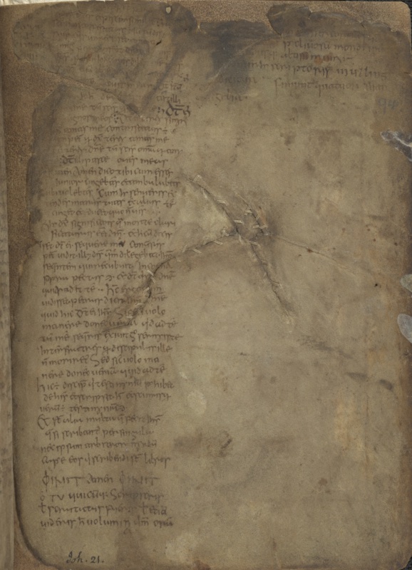 Heavily stained and darkened vellum page from the Book of Mulling, with a single narrow column of small Irish minuscule script on the left containing the end of John's Gospel and the opening of the colophon; further colophon lines naming the scribe Mulling survive at the upper right, and long diagonal tears across the blank right half of the leaf are closed with stitched vellum repairs.