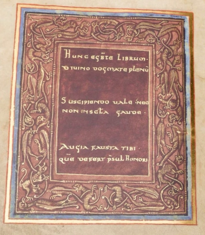 Medieval manuscript page with a blue and gold outer frame enclosing a broad purple border filled with small interlaced dragons, birds and beasts drawn in gold line; in the deeper purple central field, six lines of gold capital letters in three groups begin HUNC EGBTE LIBRUM and end QUE DEFERT PSUL HONORI