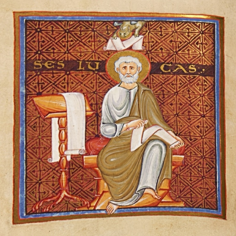 Full-page medieval miniature framed in blue and gold: an elderly white-bearded saint with a gold halo, in a white tunic and yellowish-grey mantle, sits barefoot on a block-like seat with a red cushion, holding a pen and a scroll on his knee; at left a red turned lectern with clawed feet supports a long white scroll; the red-brown background is covered with a dense gold geometric pattern, gold letters across it give his name, and at the top a small ox holding a white scroll looks down