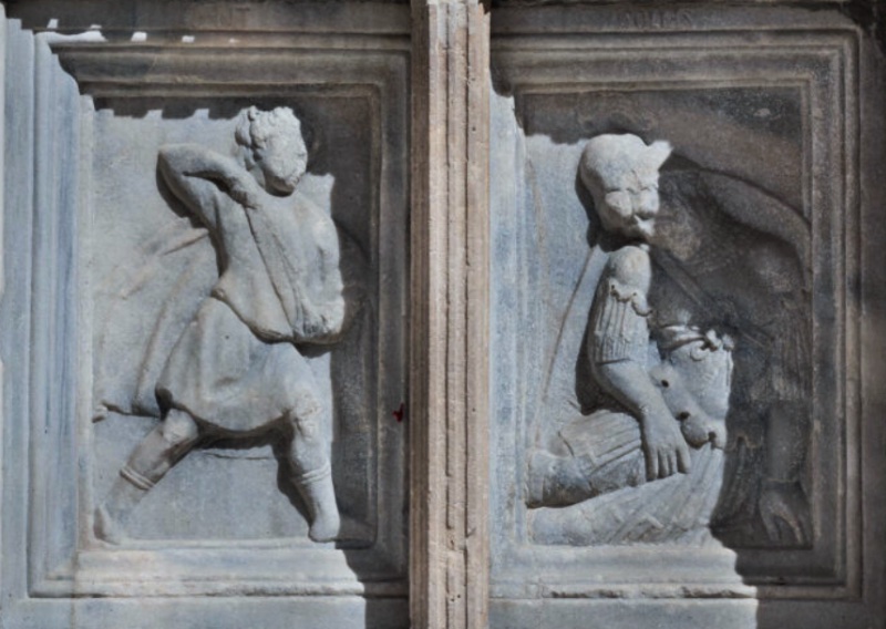 Fontana Maggiore, Perugia: young David whirling his sling, and the armoured giant Goliath collapsing struck by the stone