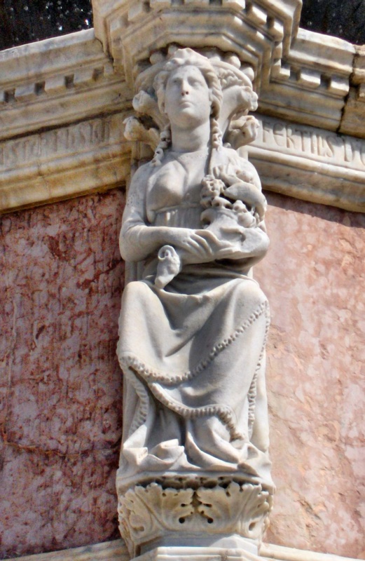 Fontana Maggiore, Perugia: enthroned statue of Augusta Perusia with braided hair, cradling a basket of fruits, legends AUGUSTA PERUSIA and FERTILIS, upper basin, 1278