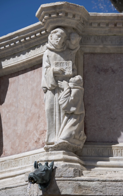 Fontana Maggiore, Perugia: group of Saint Benedict holding the open Rule inscribed AUDI FILI, with the kneeling Maurus and a second disciple, above the verse praising Fra Bevignate, upper basin, 1278