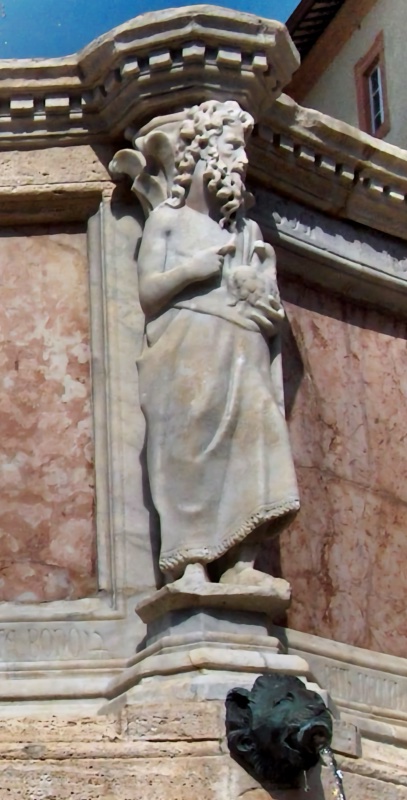 Fontana Maggiore, Perugia: statue of Saint John the Baptist bearded and turned in profile, pointing to a lamb held against his chest, above a bronze animal-head spout, 1278