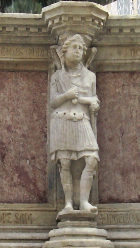 Fontana Maggiore, Perugia: statue of the Archangel Michael, a winged youth in Roman military dress with pleated tunic and greaves, gripping a sword hilt at his chest, 1278
