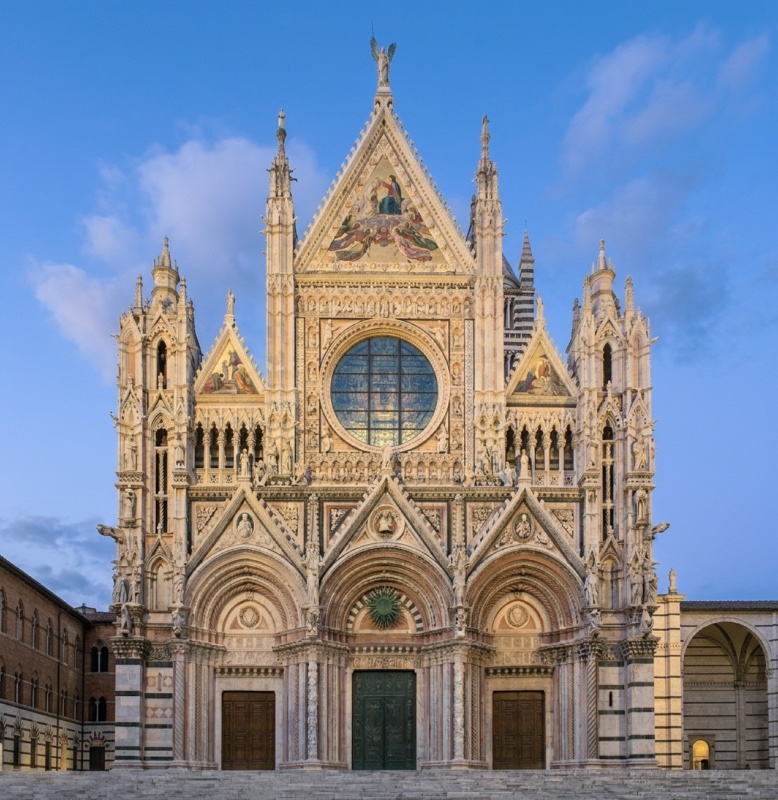 Polychrome marble Gothic cathedral façade with three deeply splayed portals below and, above, a large circular window flanked by loggias, crowned by three gabled cusps filled with gold-ground mosaics; free-standing statues project from the wall at the level of the upper cornice and along the flanking turrets.