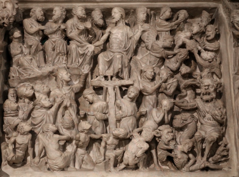 Densely carved marble relief: a bearded Christ sits enthroned at the upper centre with arms opened and chest bared; directly below his feet two bowed figures raise a cross; at the left clothed figures stand in tiered ranks with half-nude figures rising along the lower edge; at the right nude bodies are seized and inverted by horned demons, a coiled serpent and a snouted beast filling the corner.