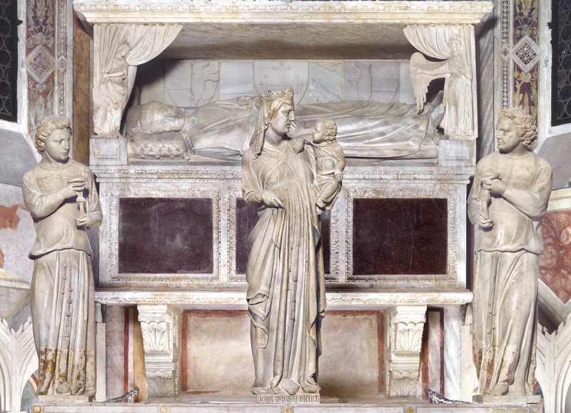 Three marble figures standing on a ledge above an altar: at the centre a crowned Virgin holding the Christ Child, who turns his head toward her; at either side a wingless young man in a long tunic with a vertical orphrey band, holding a tall candlestick. Behind and above, a recumbent effigy lies beneath a canopy whose curtains are drawn back by winged figures at the corners.