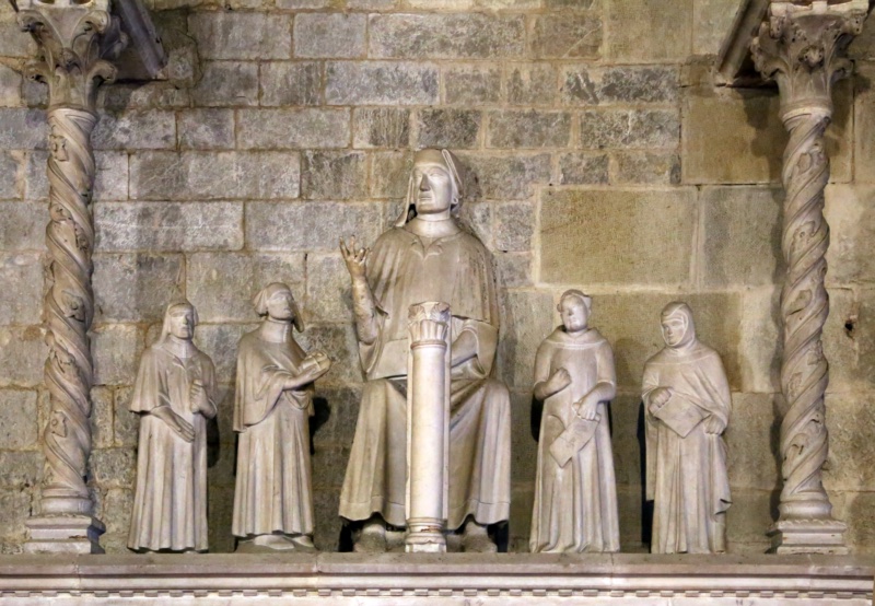 Marble statue group from the tomb of Cino da Pistoia, attributed to Agostino di Giovanni, 1337–1339: the jurist, seated at larger scale in doctor's cap and gown, raises his right hand in a teaching gesture beside a small colonnette, flanked by four smaller standing students holding books and scrolls; Pistoia Cathedral