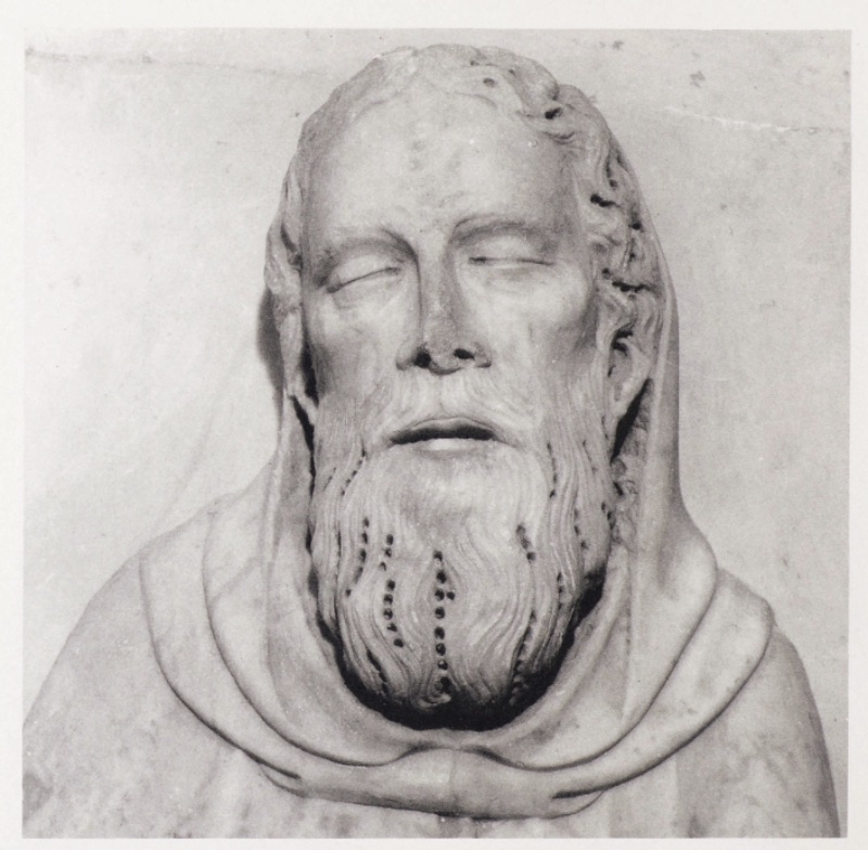 Detail of the marble head of a dead saint attributed to Giovanni di Agostino, c. 1331: an elderly bearded face framed by a monastic cowl, eyes closed, lips slightly parted, forehead marked by a vertical groove, the long wavy beard articulated by rows of drilled dots; from a dismembered shrine, Museo Diocesano d'Arte Sacra, Volterra.