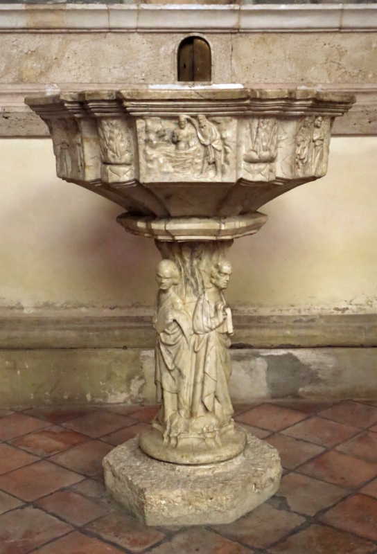 Marble baptismal font attributed to Giovanni di Agostino, 14th century, Montepulciano Cathedral: a polygonal basin carved with the Baptism of Christ and attendant figures, on a stem formed of three standing Apostles back to back, rough octagonal base