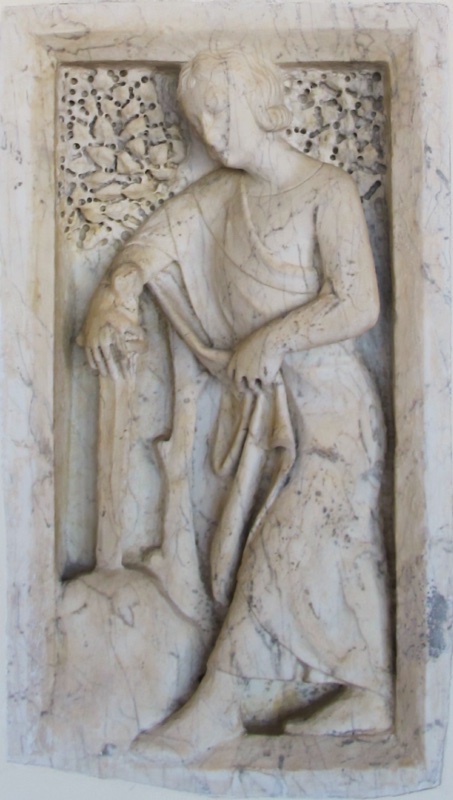 Marble relief attributed to Giovanni di Agostino: Saint Galgano, a beardless youth with wavy hair, inclines his head as he rests one hand on the hilt of a sword planted in a rock at lower left and gathers his mantle with the other, foliage in the upper corners