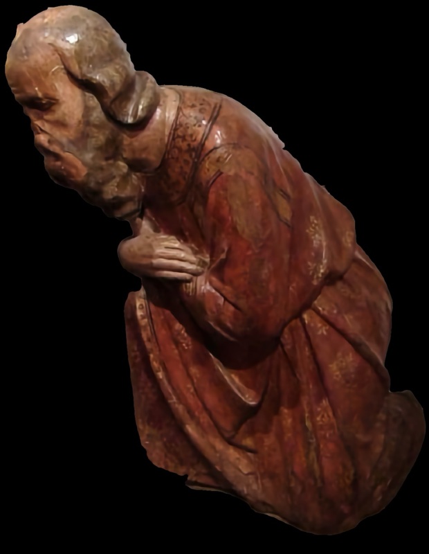 Fourteenth-century painted wooden statue of an elderly, bareheaded Magus kneeling in profile, bowed deeply forward with hands folded on his chest; his red mantle is decorated with gilded floral patterns. Maestro dei Magi di Fabriano, Pinacoteca Civica Bruno Molajoli, Fabriano.