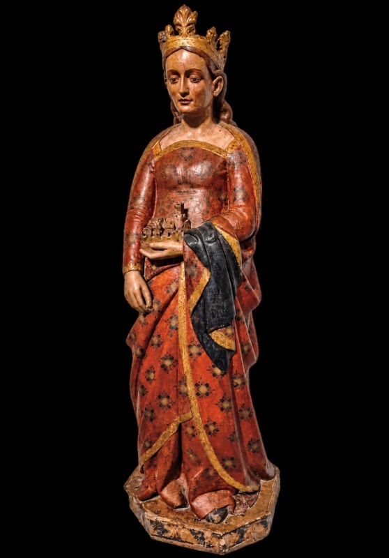 Fourteenth-century painted wooden statue of Saint Anatolia, crowned and standing in a red rosette-patterned gown with gilded borders, holding a miniature walled town with towers on her left hand; the visible paint is probably later repainting. Maestro dei Magi di Fabriano, Museo Diocesano Giacomo Boccanera, Camerino.
