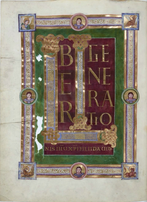 Ottonian manuscript incipit page. A large gold monogram combining the letters L and I, filled with interlace in gold, blue and white and ending in knotted terminals, stands on a deep purple panel. Beside it, tall gold capitals spell BER and GENERATIO, and a gold line beneath reads NIS IHU XPI FILII DAVID. A green field surrounds the panel, enclosed by a broad gold frame with bands of scrolling vines. Square corner fields hold the evangelist symbols: an angel at top left, an eagle at top right, a lion at bottom left and an ox at bottom right. Circular medallions at the middle of each side contain busts of young, beardless men on gold grounds. The parchment is torn and holed in the green area at left