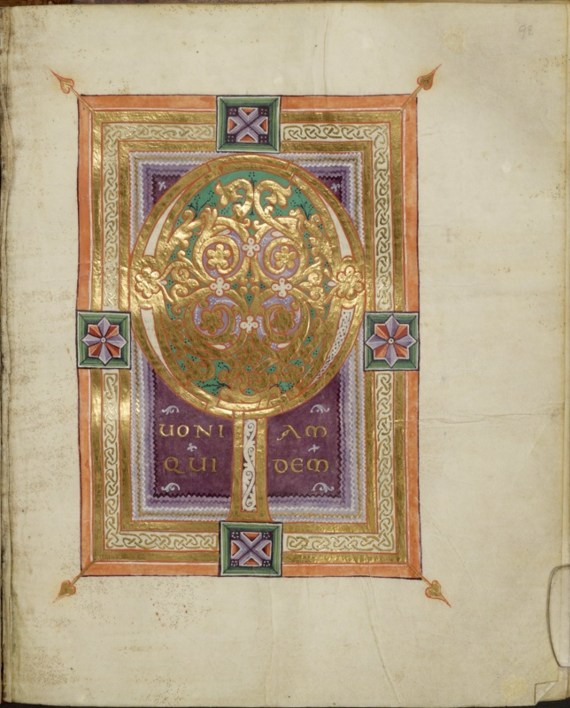 Ottonian manuscript incipit page. On a deep purple panel with stepped lilac edges, a monumental gold initial Q fills the upper part: its oval bowl encloses a green field with symmetrical gold vine scrolls, gold rosettes and small white quatrefoils on lilac grounds, and its tail descends as a straight vertical stem filled with a white scroll pattern. Beside the stem, gold capitals read UONI AM / QUI DEM, completing QUONIAM QUIDEM, with small white sprigs scattered on the purple. The frame consists of orange, gold and white bands with gold interlace. Bevelled square fields at the midpoints of the sides hold geometric motifs: a saltire pattern at top and bottom, eight-pointed stars at left and right. Heart-shaped gold finials project diagonally from the outer corners