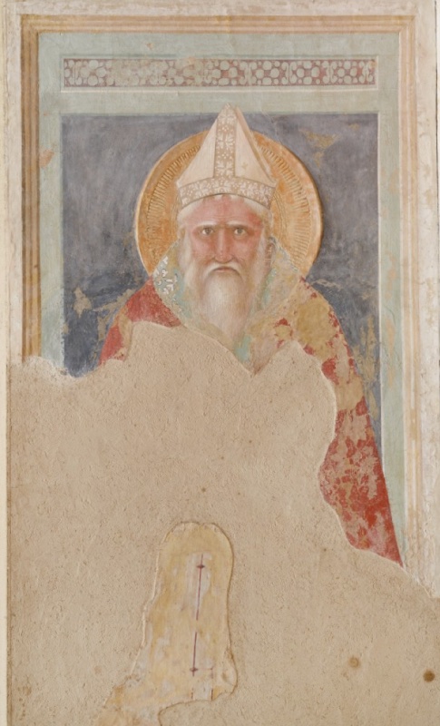 Fresco of Saint Blaise, frontal half-length bishop with a white mitre and long white beard, wide staring eyes, in a red vestment, against a dark blue ground in a green frame with a pearl-pattern frieze; the lower half is lost and filled with neutral plaster