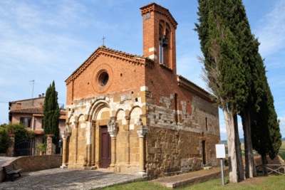 Romanesque church of San Pietro in Villore at San Giovanni d'Asso: stone lower façade with blind arcades and carved portal, brick upper storey with oculus, bell-gable and cypresses