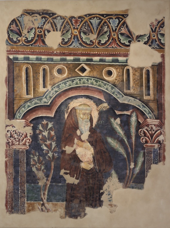 Fragmentary fresco of Saint William of Malavalle in a brown habit, holding an object beneath a trilobed arch, flanked by plants, with a divine hand above