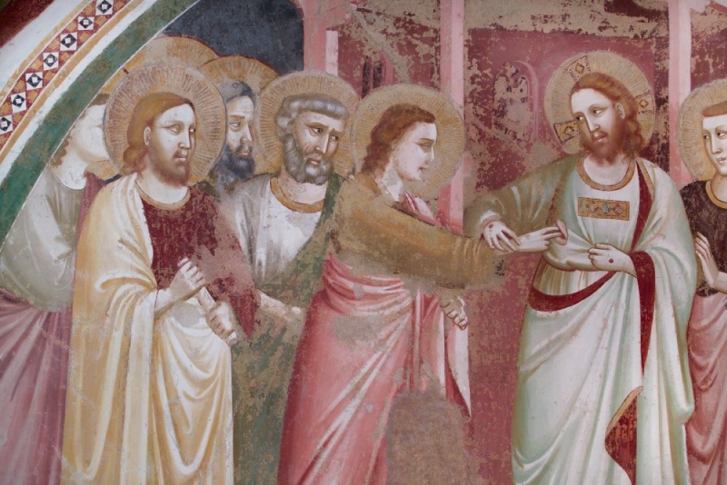 Detail of a fourteenth-century fresco: Christ, with cruciform halo and a red nail-wound on his extended right hand, draws aside his mantle at the breast while a youthful figure with long auburn hair reaches to touch the wound. Behind press haloed apostles, including grey-haired Peter, before rose-coloured architecture.