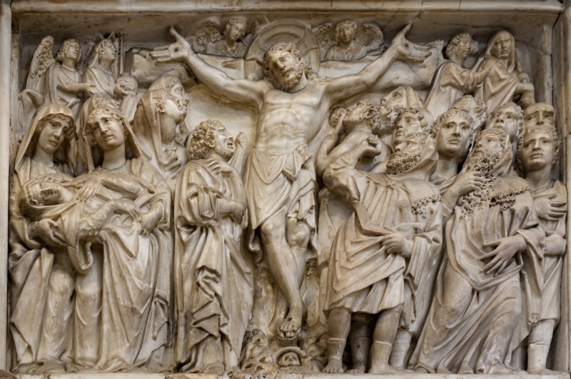 High-relief marble panel dominated by the nude body of the crucified Christ at its centre, arms outstretched and head fallen to one side; at the left a compact group of veiled women supports the swooning Virgin, while at the right a dense crowd of individuated male heads gesture upward toward the cross, angels leaning in from the upper corners.