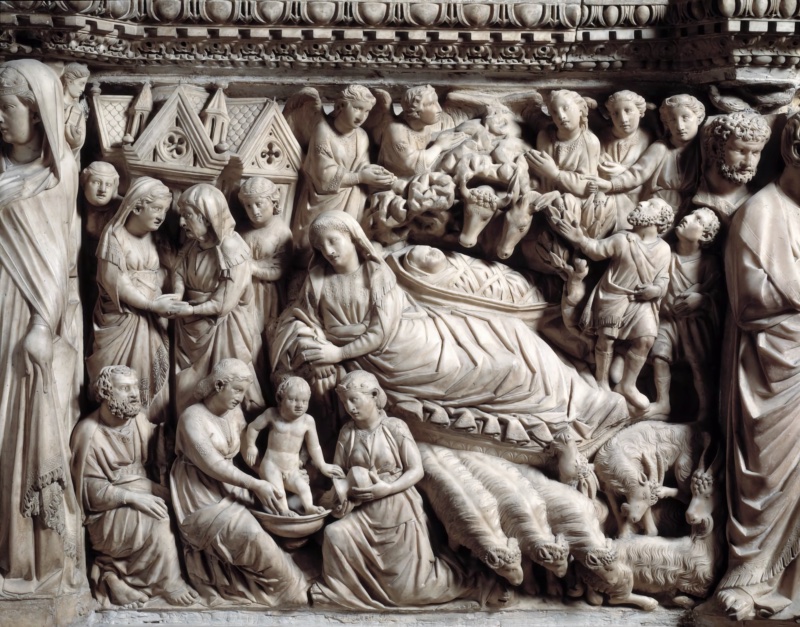 Densely carved marble relief: at the upper left two women meet before a small gabled building; across the centre a veiled Virgin reclines on a thick mattress, her head inclined downward, with the swaddled Child in a manger above her flanked by the heads of an ox and an ass; angels and shepherds occupy the right, two kneeling women bathe a standing nude infant in a basin at the lower centre, a bearded Joseph sits at the lower left, and sheep and goats fill the lower right corner.