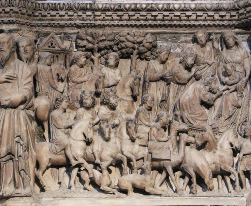 Crowded marble relief filled with horses and camels seen at varying angles, their heads crowded together and dogs running beneath their hooves; grooms move among them, a broad tree rises at the centre, and at the upper right a veiled and crowned Virgin sits enthroned with the Child as a bearded man bows before her and a second figure presents a covered vessel.